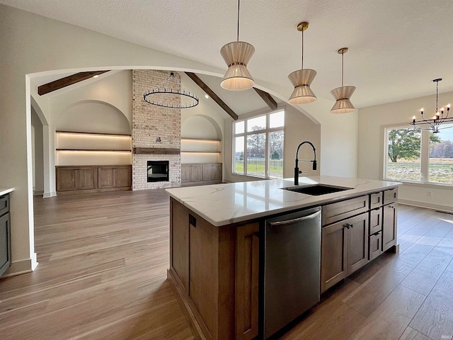 kitchen with stainless steel dishwasher, a wealth of natural light, sink, and vaulted ceiling with beams