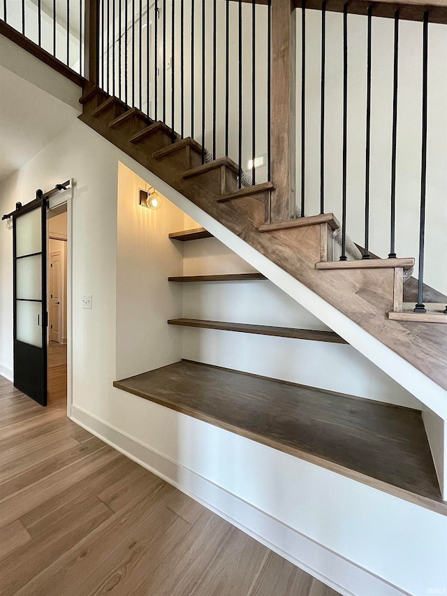 stairway with hardwood / wood-style floors and a barn door