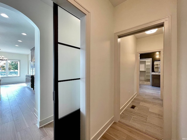 hallway featuring an inviting chandelier and light hardwood / wood-style flooring