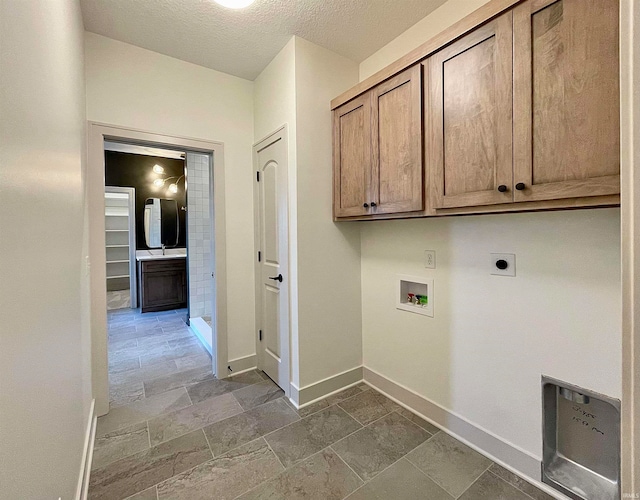 laundry room with electric dryer hookup, washer hookup, cabinets, and a textured ceiling