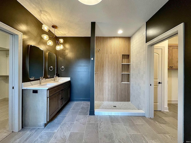 bathroom featuring walk in shower, vanity, and a textured ceiling