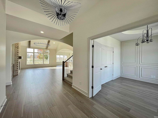 hall with a chandelier, lofted ceiling, and dark hardwood / wood-style floors