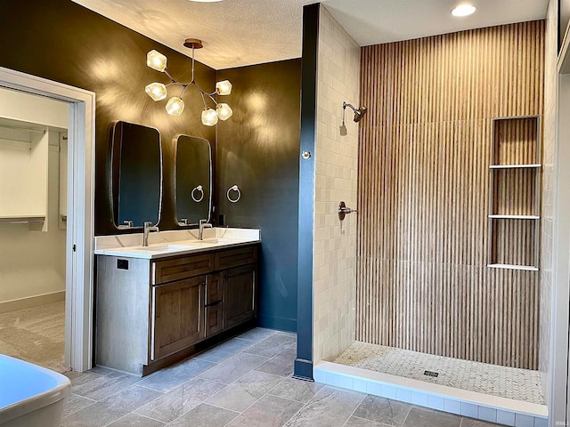 bathroom featuring vanity, an inviting chandelier, tiled shower, and a textured ceiling