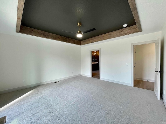 unfurnished room with ceiling fan, carpet flooring, and a tray ceiling