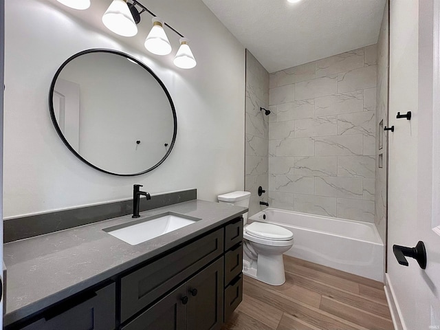 full bathroom featuring vanity, a textured ceiling, hardwood / wood-style floors, toilet, and tiled shower / bath