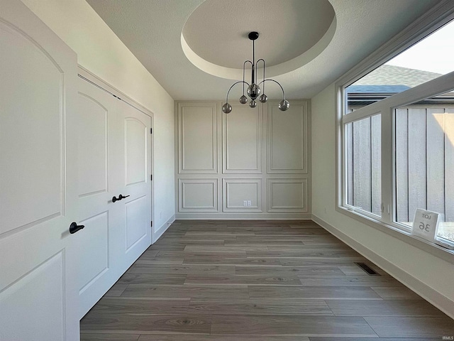 unfurnished dining area featuring dark wood-type flooring and a tray ceiling