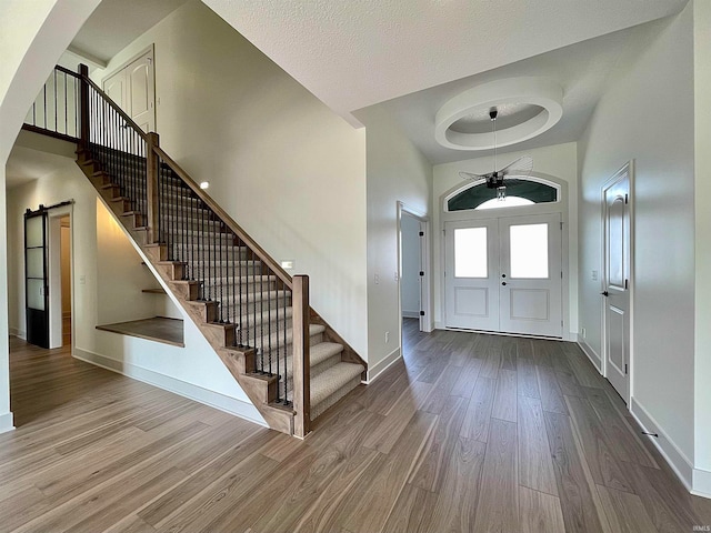 foyer entrance featuring a barn door, wood-type flooring, a high ceiling, and french doors