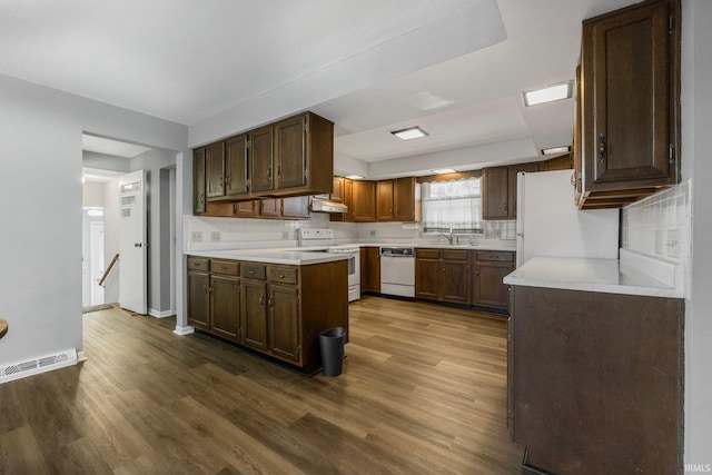 kitchen with white appliances, dark hardwood / wood-style floors, and dark brown cabinets