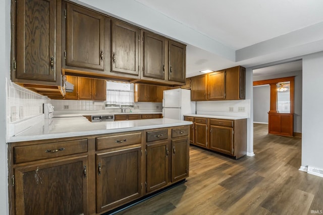 kitchen with white refrigerator, range, sink, decorative backsplash, and dark wood-type flooring