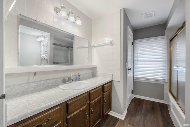 bathroom with vanity, hardwood / wood-style flooring, and enclosed tub / shower combo