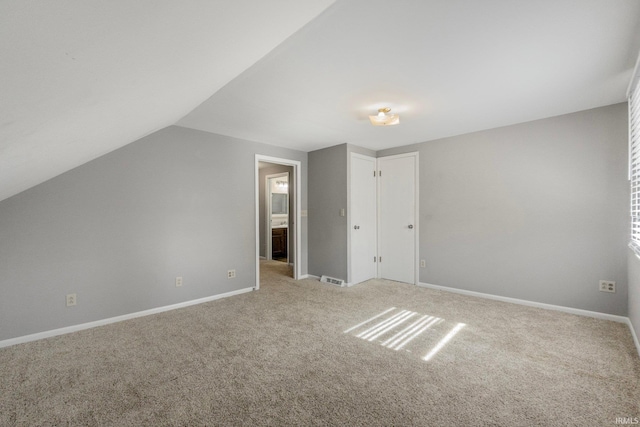 bonus room with light colored carpet and vaulted ceiling