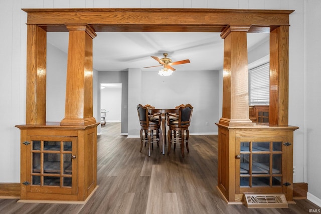 dining space with ceiling fan, ornate columns, and dark hardwood / wood-style floors