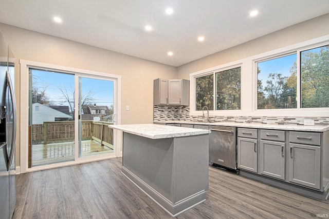 kitchen featuring gray cabinetry, appliances with stainless steel finishes, dark hardwood / wood-style floors, decorative backsplash, and a center island