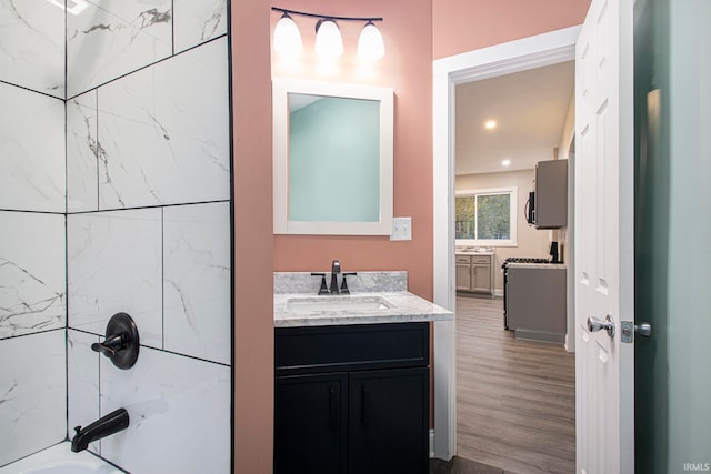 bathroom featuring hardwood / wood-style floors, vanity, and tiled shower / bath combo