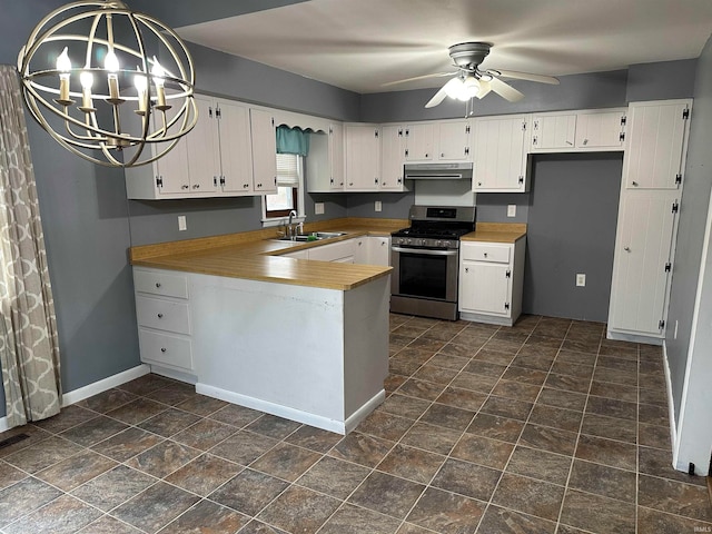 kitchen featuring white cabinetry, sink, ceiling fan with notable chandelier, decorative light fixtures, and stainless steel gas range oven