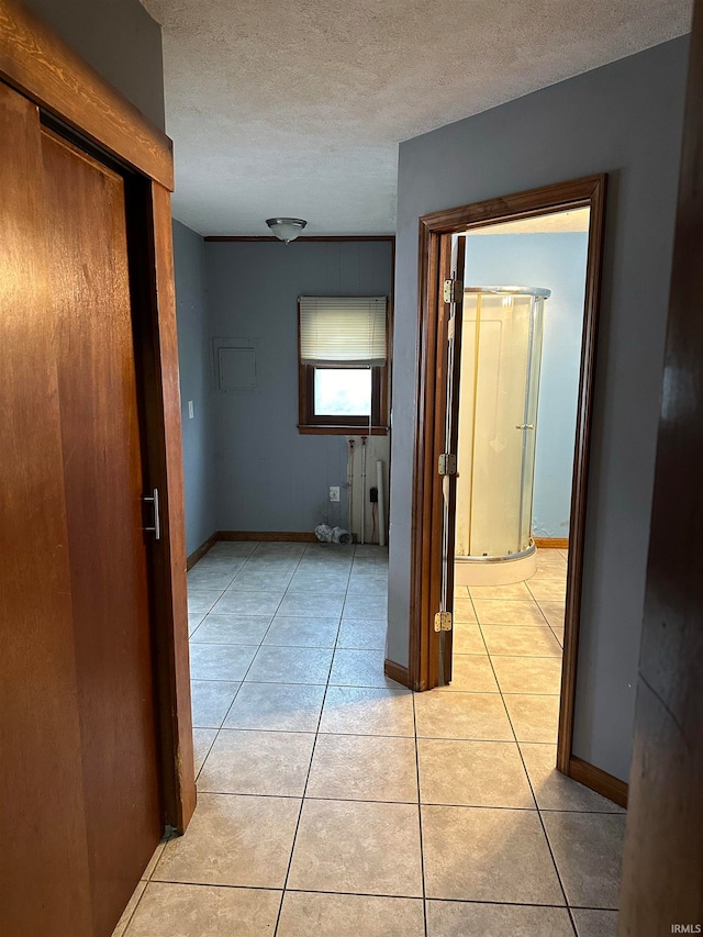 hall featuring a textured ceiling and light tile patterned floors