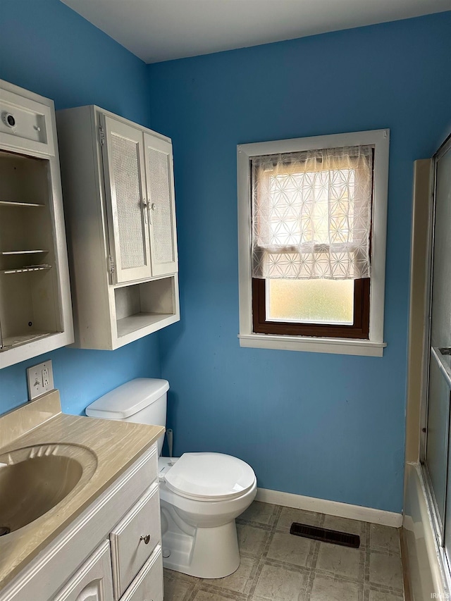 full bathroom featuring toilet, vanity, and shower / bath combination with glass door