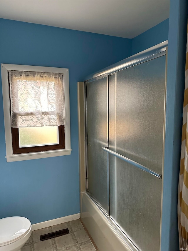 bathroom featuring bath / shower combo with glass door and toilet