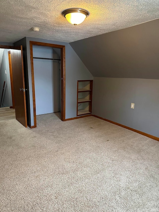 bonus room featuring a textured ceiling, carpet flooring, and vaulted ceiling