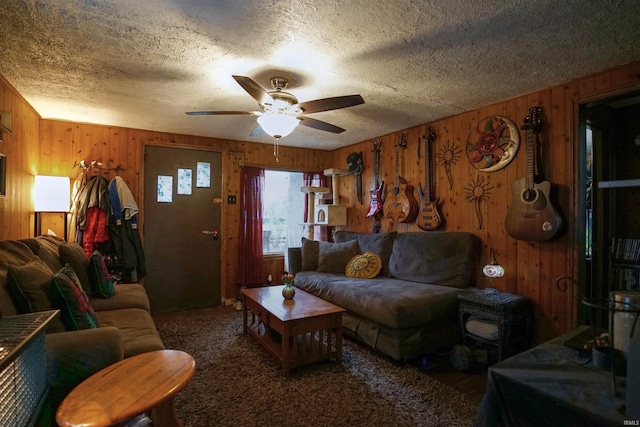 carpeted living room with a textured ceiling, wooden walls, and ceiling fan