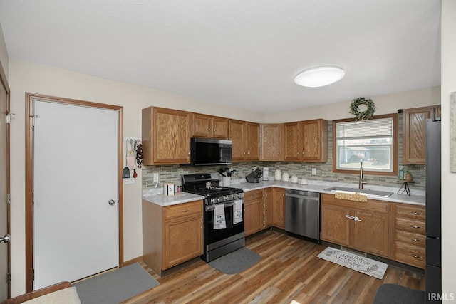 kitchen featuring dark wood-type flooring, backsplash, sink, and stainless steel appliances