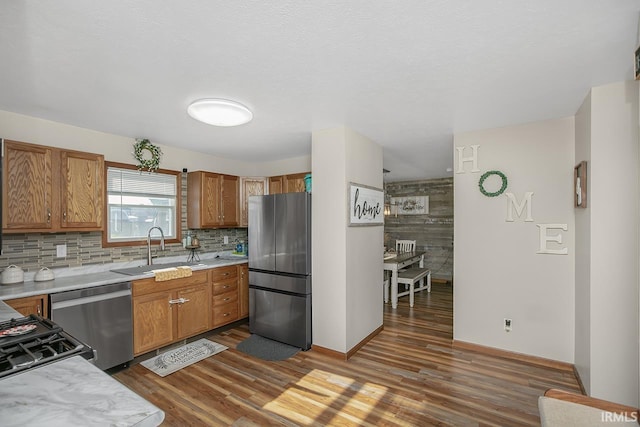 kitchen with appliances with stainless steel finishes, dark wood-type flooring, sink, and tasteful backsplash