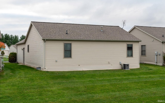 back of property with central AC unit and a yard