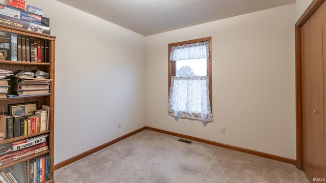 unfurnished bedroom featuring a textured ceiling and light colored carpet