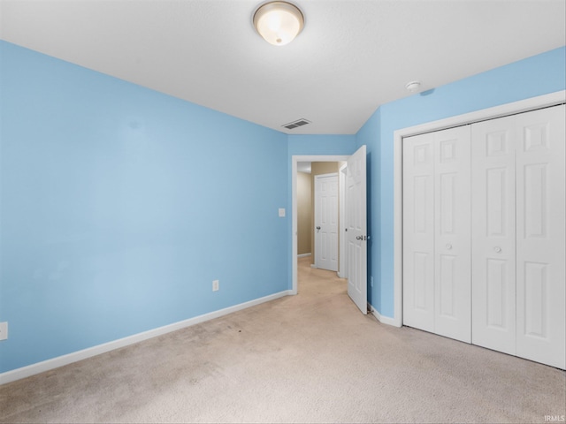 unfurnished bedroom with light colored carpet and a closet