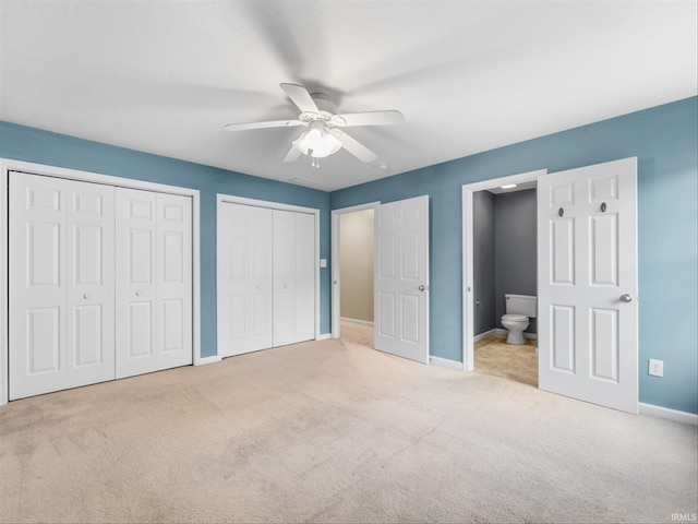 unfurnished bedroom with ceiling fan, ensuite bath, multiple closets, and light colored carpet