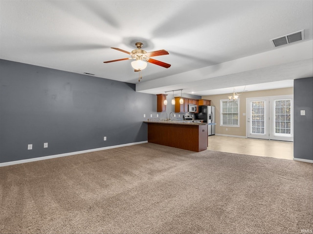 unfurnished living room featuring sink, light carpet, and ceiling fan with notable chandelier