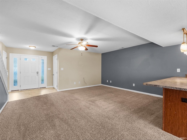 unfurnished living room featuring carpet, a textured ceiling, and ceiling fan