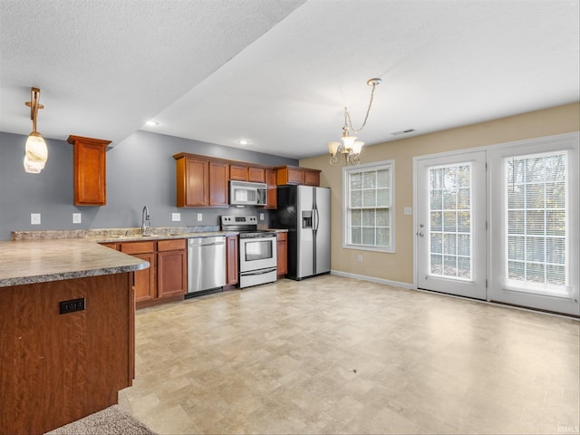 kitchen with a notable chandelier, sink, a textured ceiling, pendant lighting, and appliances with stainless steel finishes