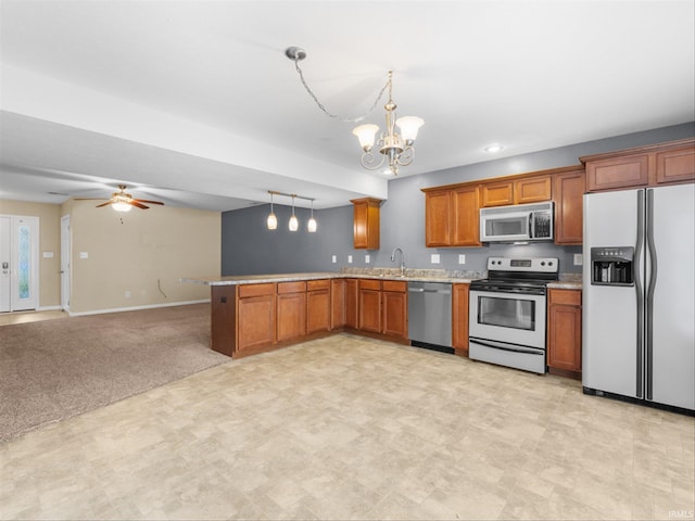 kitchen with appliances with stainless steel finishes, hanging light fixtures, sink, kitchen peninsula, and light colored carpet