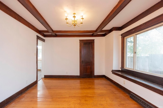 spare room featuring light hardwood / wood-style flooring, beam ceiling, and an inviting chandelier