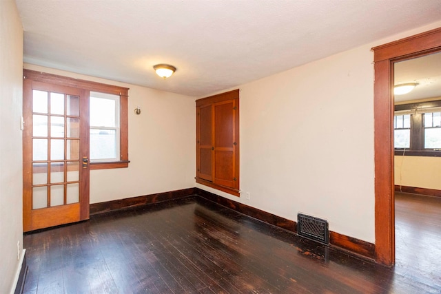 empty room featuring dark hardwood / wood-style flooring and a healthy amount of sunlight