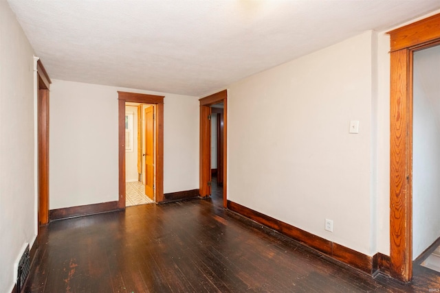 spare room with dark wood-type flooring and a textured ceiling