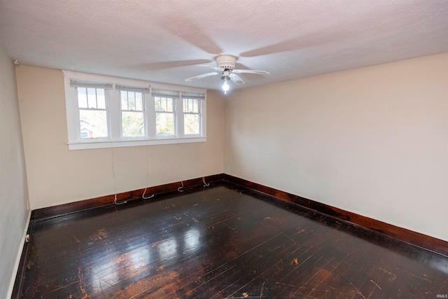 empty room featuring dark hardwood / wood-style flooring, a textured ceiling, and ceiling fan