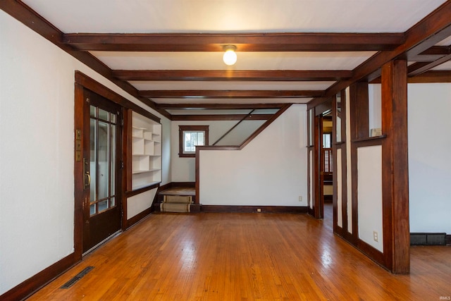 empty room with hardwood / wood-style floors and beamed ceiling