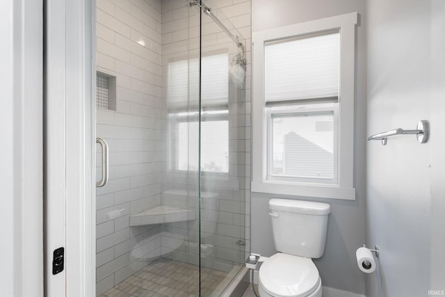 bathroom featuring toilet and a shower with shower door