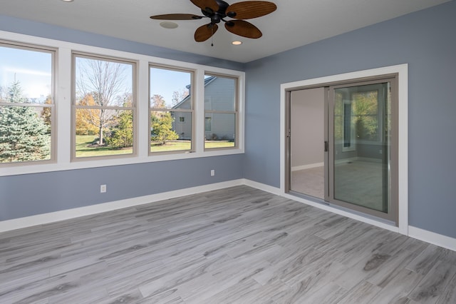 unfurnished sunroom with ceiling fan