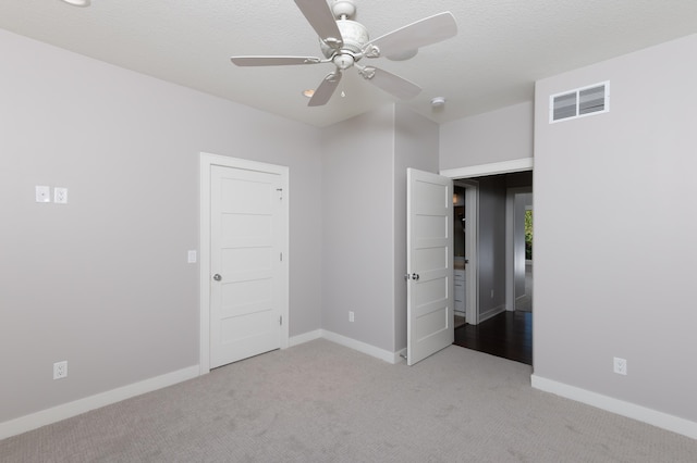 unfurnished bedroom featuring a textured ceiling, light colored carpet, and ceiling fan