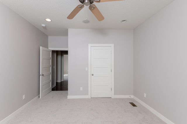 unfurnished bedroom with a textured ceiling, light colored carpet, and ceiling fan