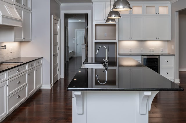 kitchen with wine cooler, white cabinetry, and a kitchen island with sink