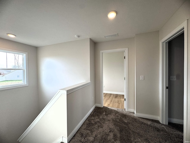 hall with visible vents, baseboards, and carpet