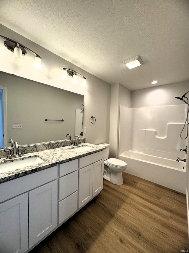 full bath with a sink, toilet, wood finished floors, and double vanity