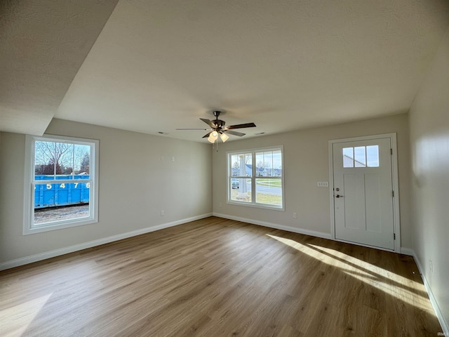 entryway featuring baseboards, wood finished floors, and a ceiling fan