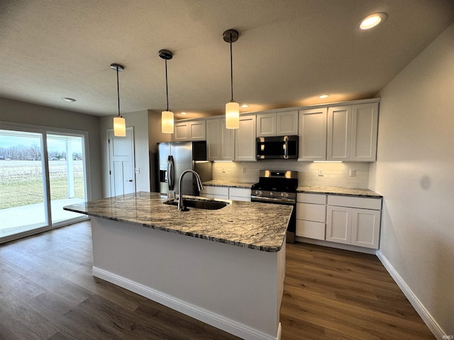 kitchen with tasteful backsplash, baseboards, dark wood finished floors, stainless steel appliances, and a sink