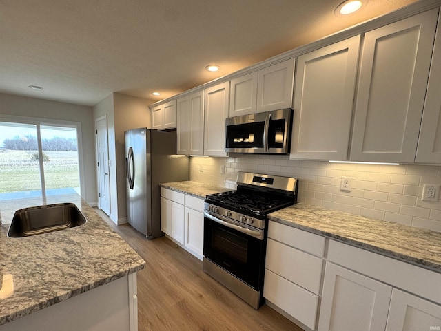 kitchen with tasteful backsplash, light wood-type flooring, light stone counters, recessed lighting, and stainless steel appliances