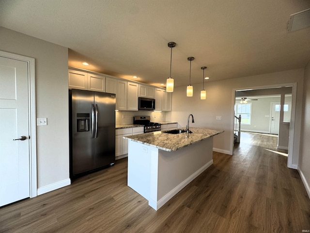 kitchen with a sink, ceiling fan, dark wood-style flooring, appliances with stainless steel finishes, and a kitchen island with sink